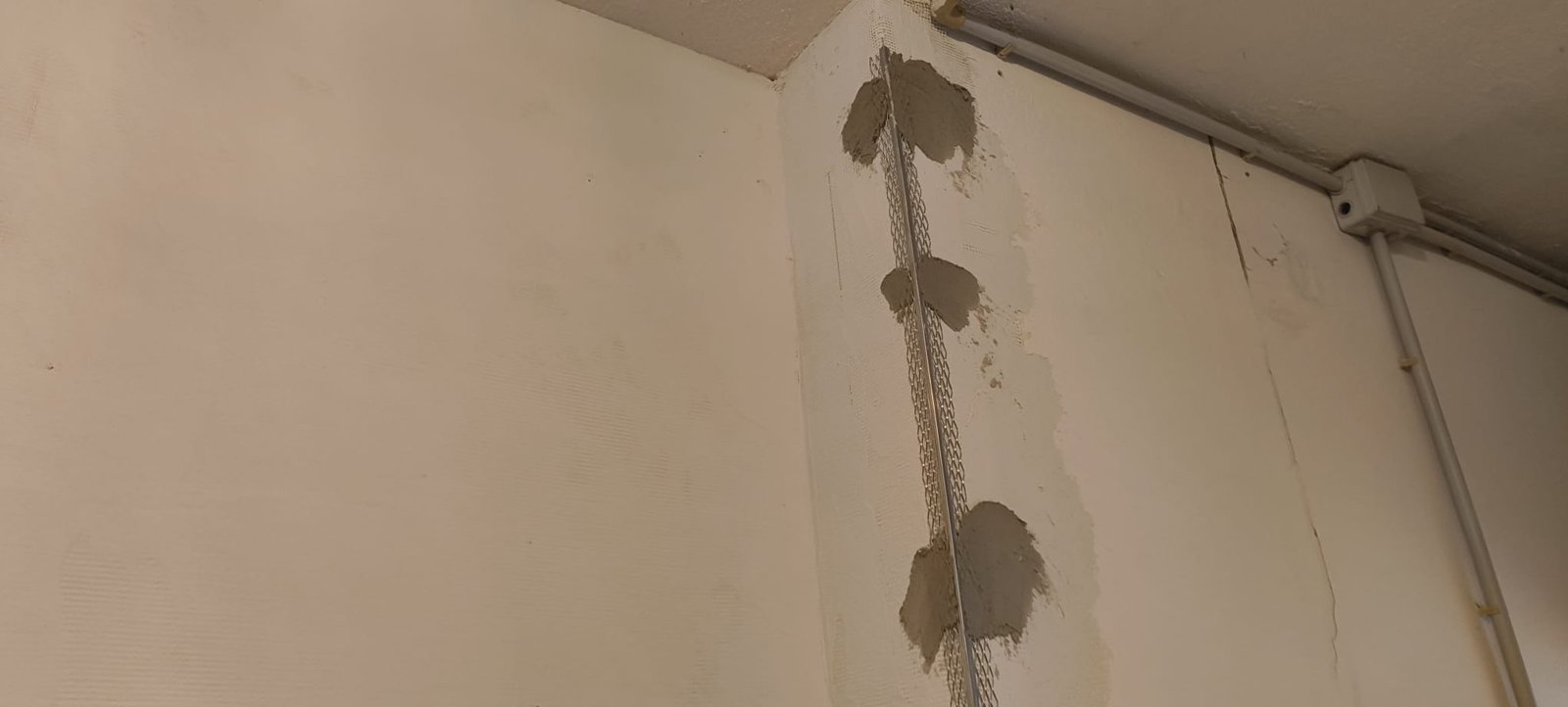 Applicazione di paraspigoli e punti di malta sullo spigolo di una parete